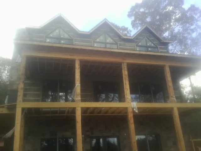 Dormers and porch framing on a large log home under construction — Roof Coating work by our crew in Mooresboro