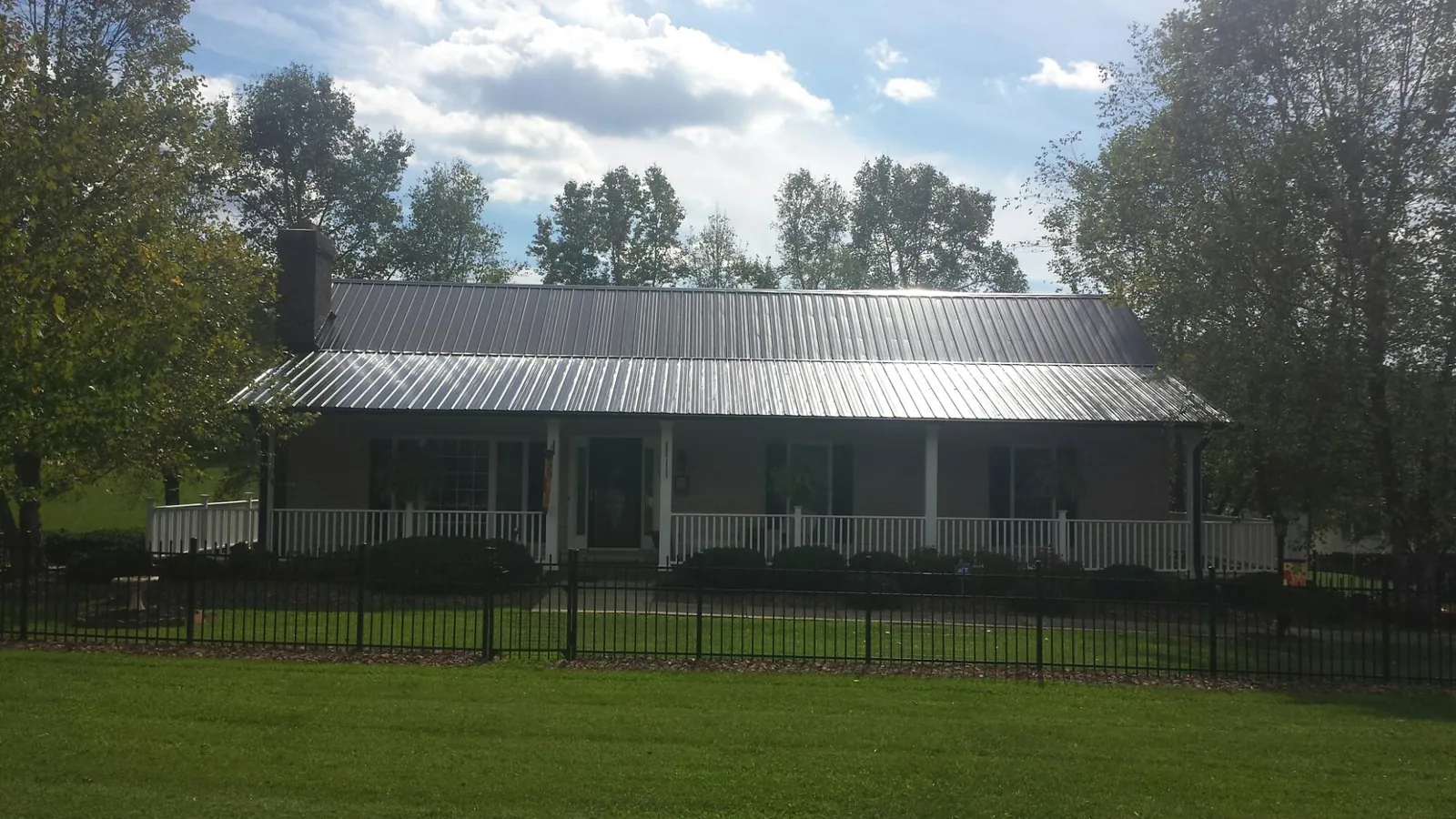 Gray metal roof on a brick ranch with a full width front porch — Gutter Guard Installation work by our crew in Mooresboro