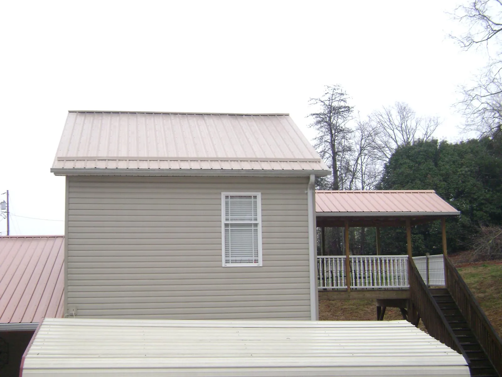 Tan metal roofs on a two story addition and attached porch, from a Roof Replacement job in Mooresboro