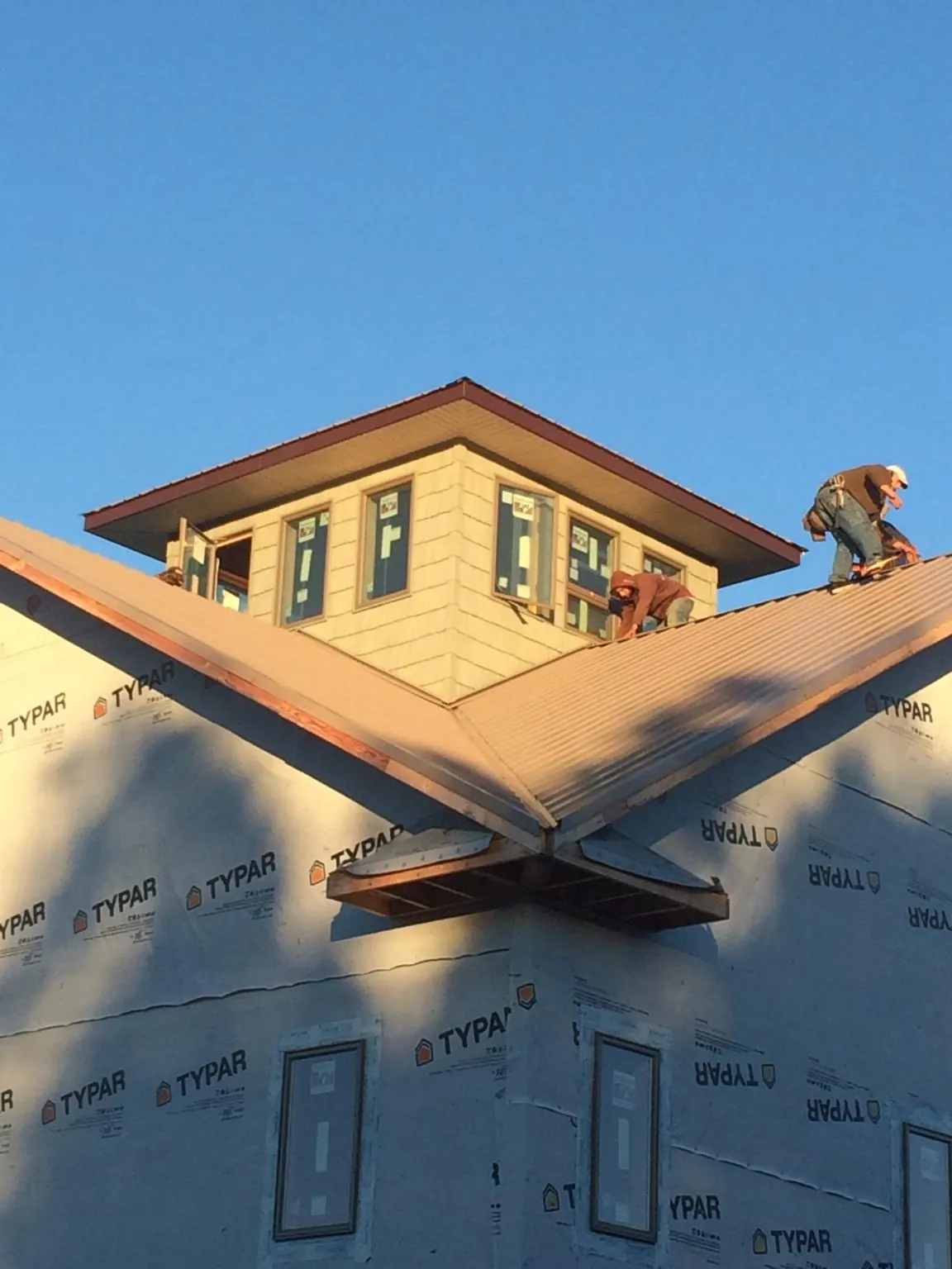 Roofers working around a rooftop cupola on a new metal roof at sunset — Roof Waterproofing in Mooresboro by Roofing Brothers